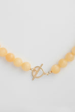 Load image into Gallery viewer, Necklace with yellow beads and a gold clasp on a light grey background