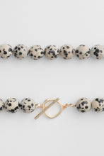 Load image into Gallery viewer, Beaded necklace details shot with dalmatian jasper stones and a gold toggle clasp on a white background
