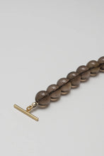 Load image into Gallery viewer, Bracelet with brown beads and a gold clasp on a light gray background
