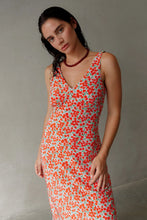 Load image into Gallery viewer, Woman wearing a red necklace and floral dress with a plain background
