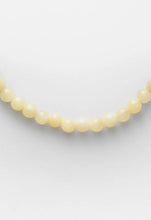 Load image into Gallery viewer, A close-up of a pale yellow beaded strand, likely a necklace, against a plain light gray background.
